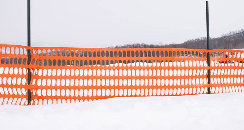 High noticeable orange plastic snow fence by T-posts.