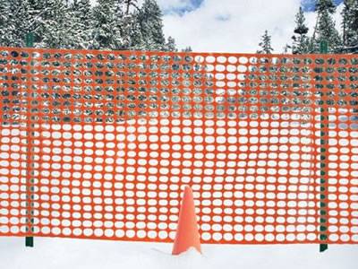 High visible orange snow fence controlling snow drift.